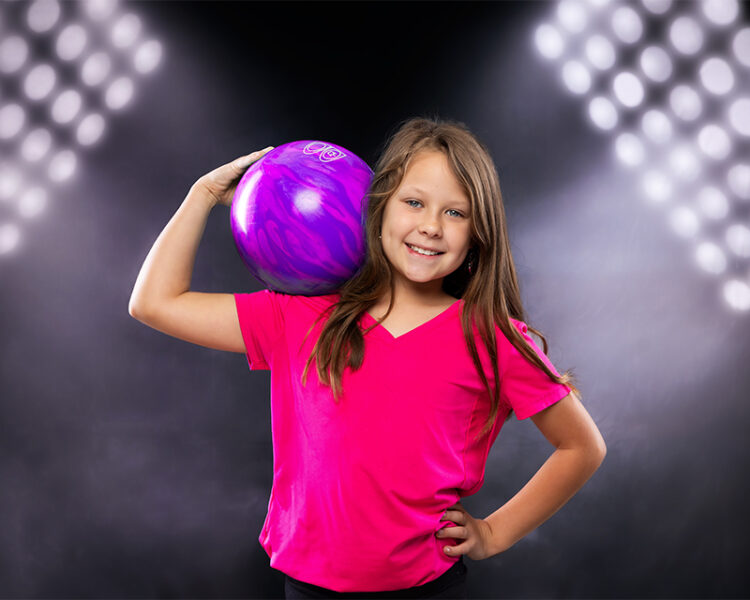 Young girl posing with bowling ball in a studio in Mebane North Carolina