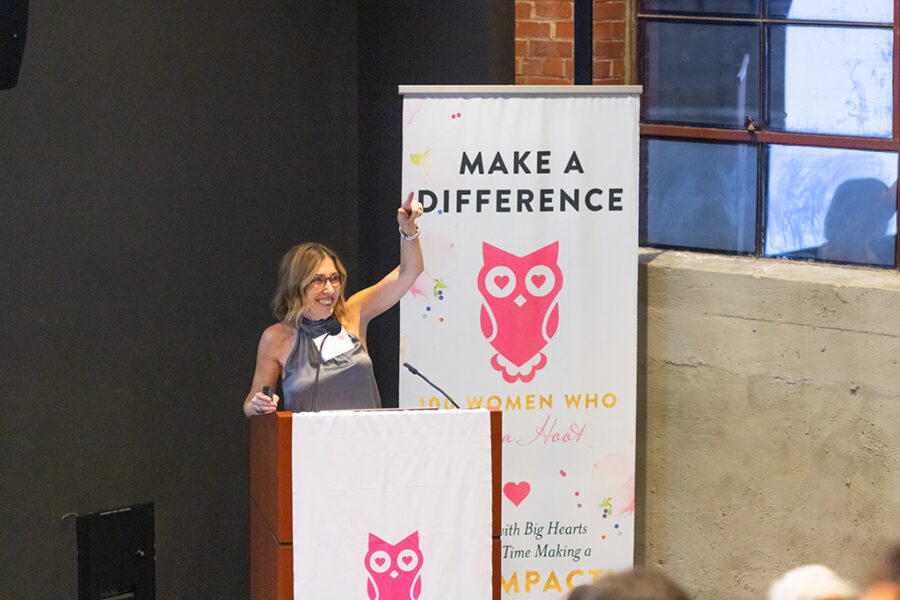 Event photography featuring a speaker at a podium gesturing to someone in the crowd.